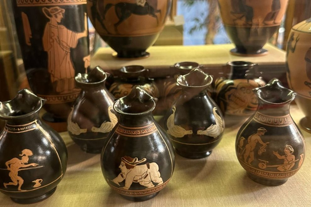A display of small, intricately painted ancient-style pottery vases with mythological and figurative designs.