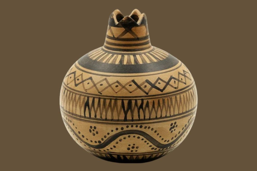 Ancient Greek pottery vessel with geometric patterns and a pomegranate-shaped top.