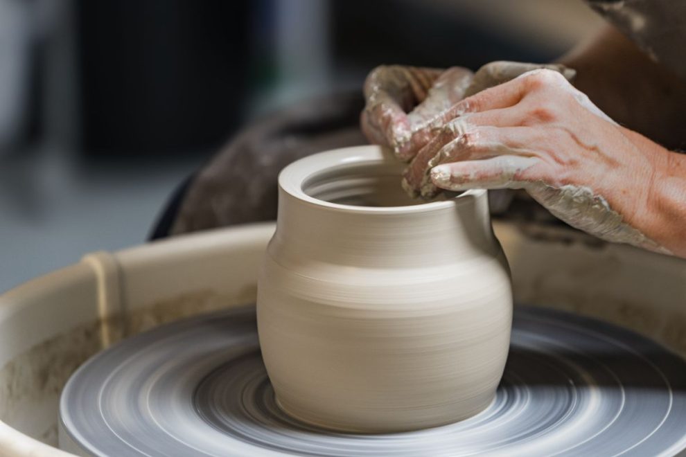 Hands shaping clay on a potter’s wheel, a key technique in creating modern Greek pottery. 