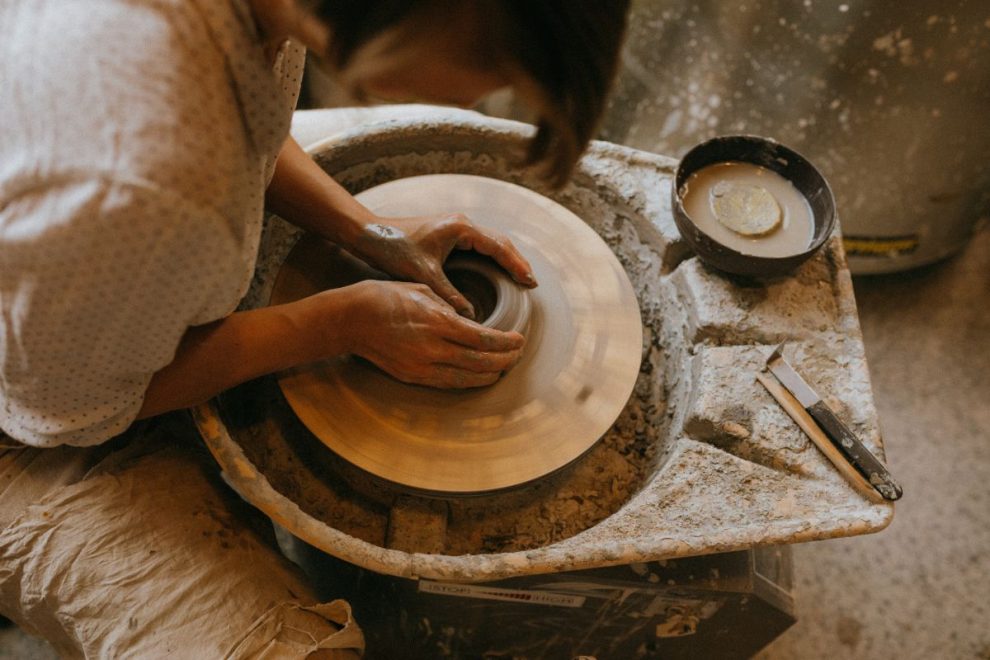 hands shaping clay on a pottery wheel during ceramic making process
