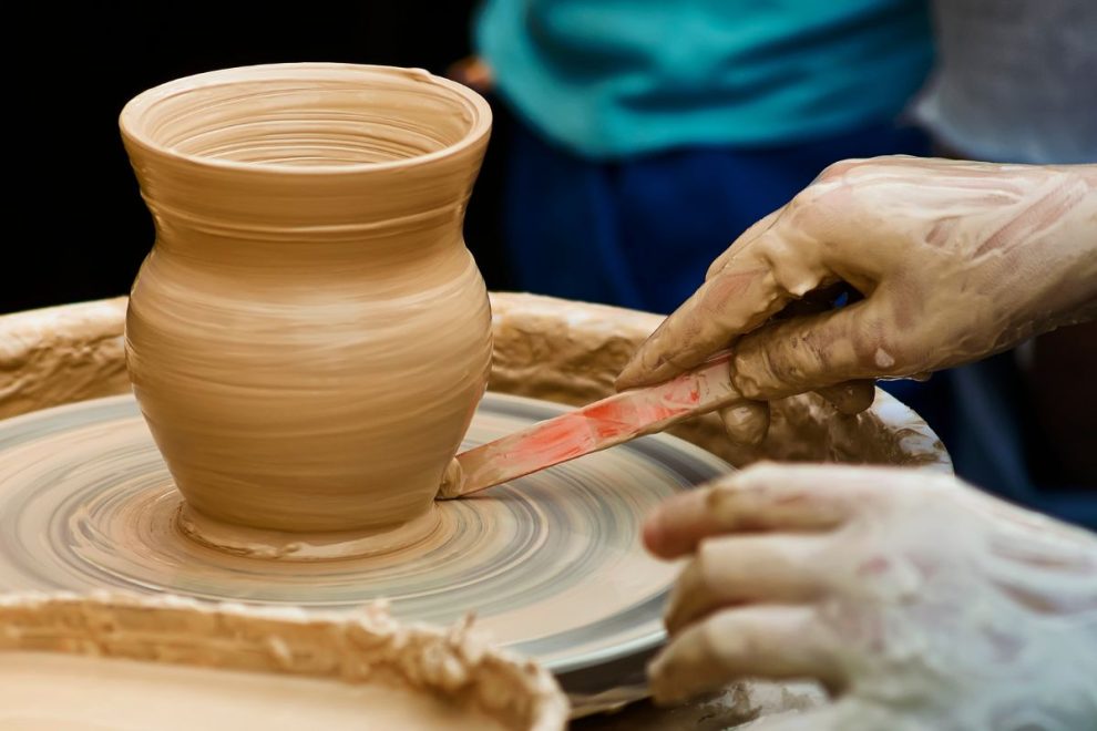 shaping a clay vase on a pottery wheel using traditional hand tools
