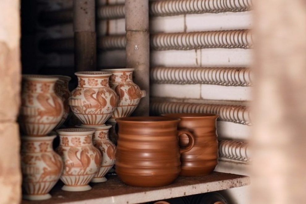 Handcrafted ceramic vessels inside a modern electric kiln during the pottery firing process.