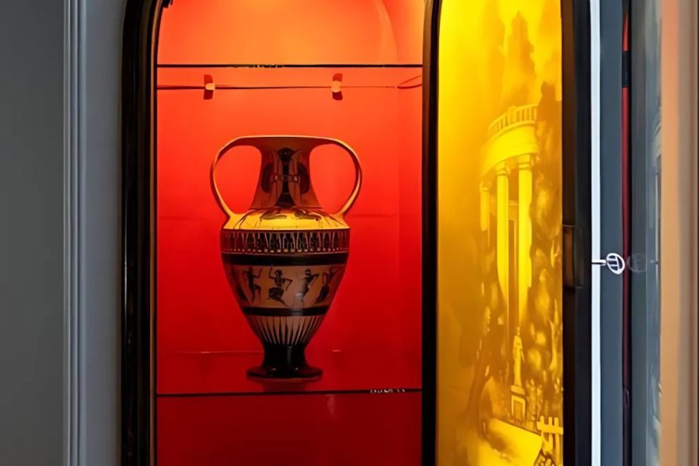 Ancient Greek amphora displayed in a museum case with red and yellow background lighting.