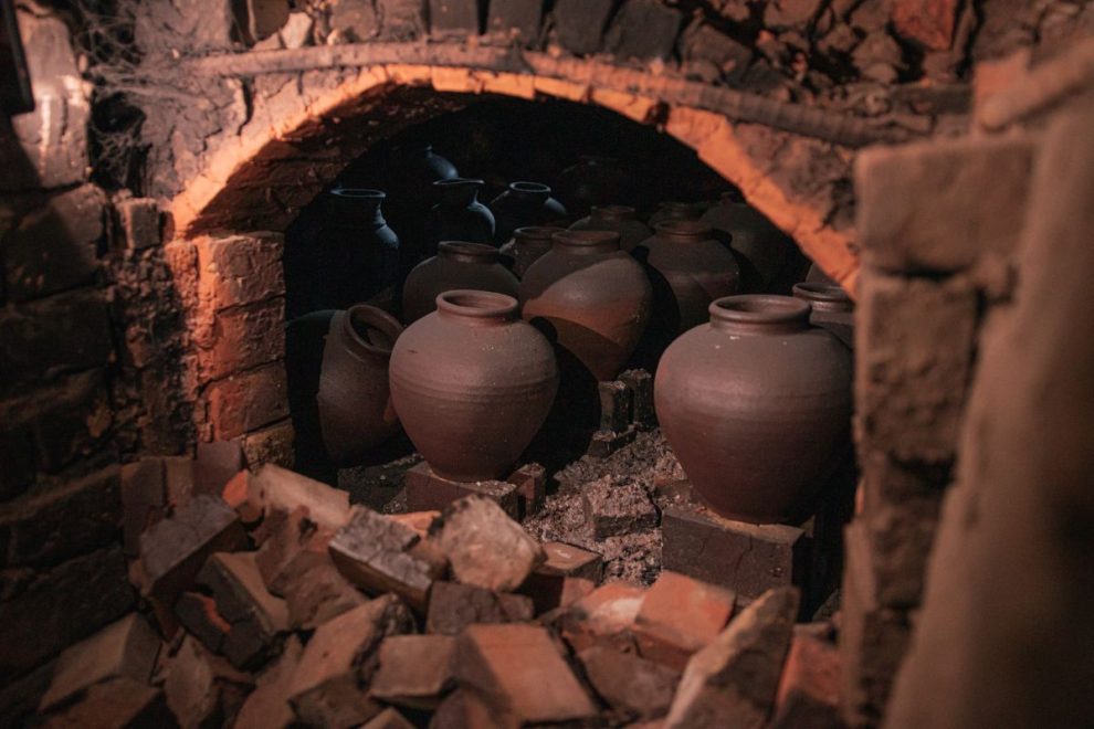 Ancient pottery kiln with clay vessels inside during the firing process. 