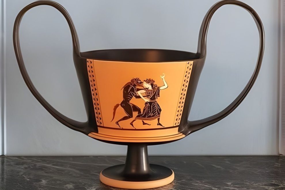 large kantharos vase with twin handles and a black figure scene on a pedestal, displayed indoors for an ancient greek pottery feature