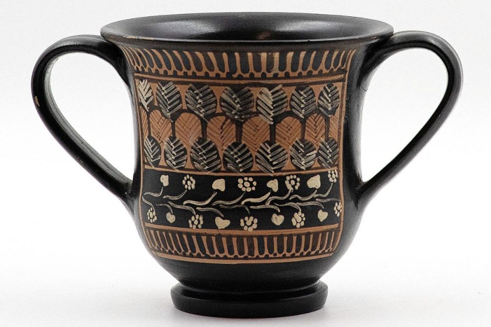 sessile kantharos with two handles and leaf-vine motifs, an ancient greek pottery wine cup photographed on a plain background