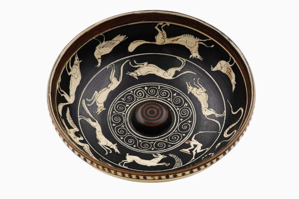Decorated ancient Greek phiale featuring animal figures and spiral designs used in religious libation rituals.