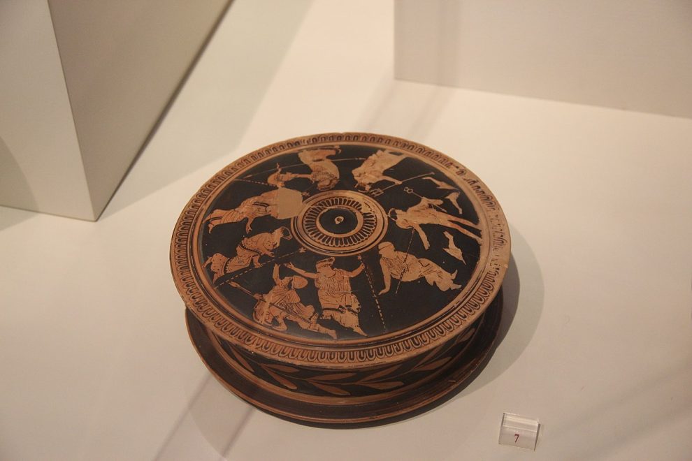 Ancient Greek red-figure pyxis with lid showing running warriors, photographed in the National Archaeological Museum of Athens.