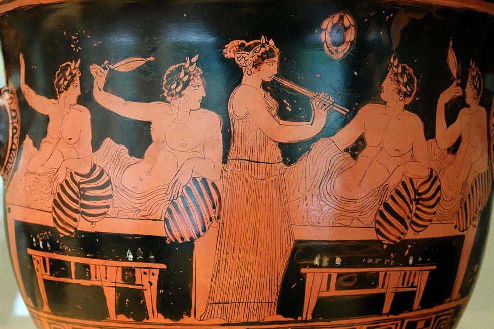 Ancient Greek symposium scene on an Attic red-figure bell-krater by the Nikias Painter, showing banqueters playing kottabos while a musician plays the aulos.